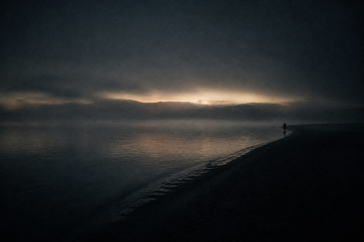 A lone figure looking out over dark water toward a thin line of light